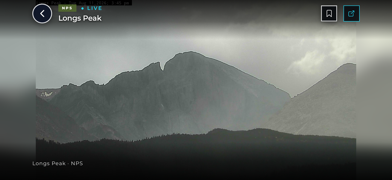 Live camera view of the Diamond face of Longs Peak under storm light, seen full-screen in UpCanyon